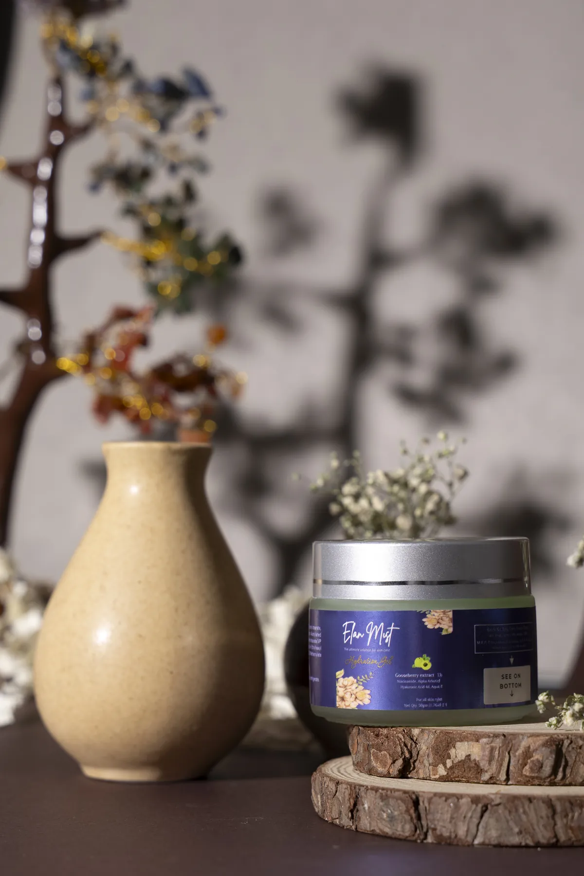 Elanmist HydroBoost Gel jar beside a ceramic vase and a small decorative tree